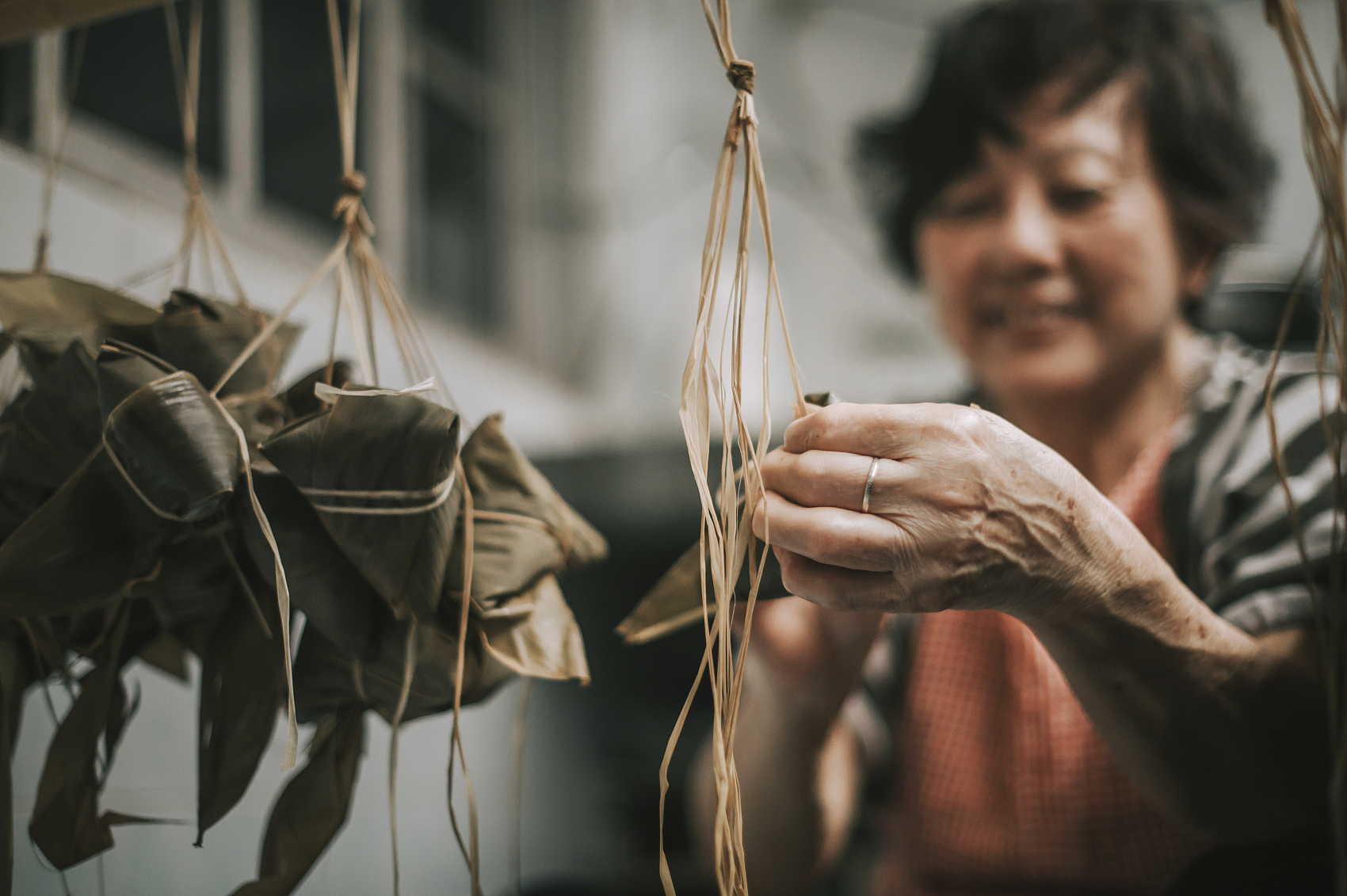 一位年长的亚洲华人妇女在她的厨房里准备粽子，把配料包好，为端午节做准备.jpg